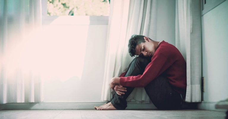 Man sits on floor looking pensively.