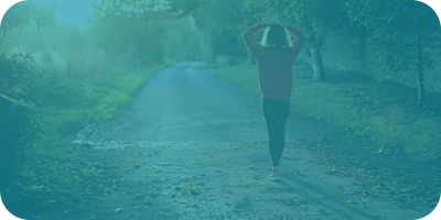 Woman walking down a path with her hands on her head